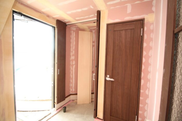 1階玄関周辺の建具と、壁紙施工前のパテ処理を行った壁面